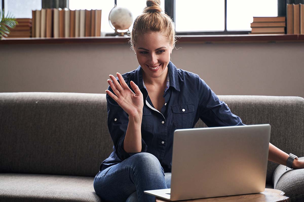 a person waves at their computer interviewing for online behavioral health jobs