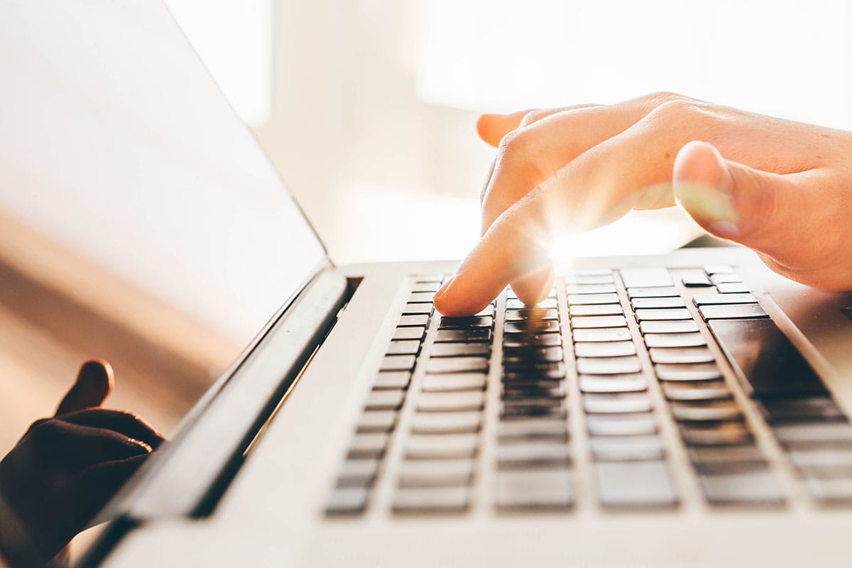 a person typing on a laptop creating a cover letter for behavioral health technician