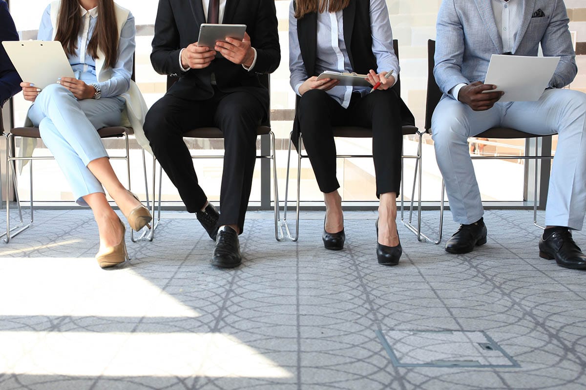 the torsos and legs of people seated in line for interviews for addiction treatment jobs in florida