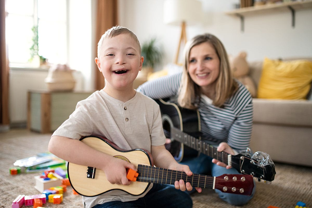 someone with one of many working in mental health watches as a child with Down syndrome plays a guitar