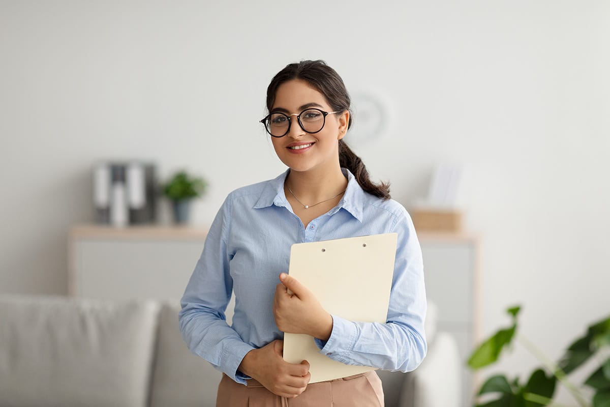 a social and community service manager holds a folder smiling at the camera