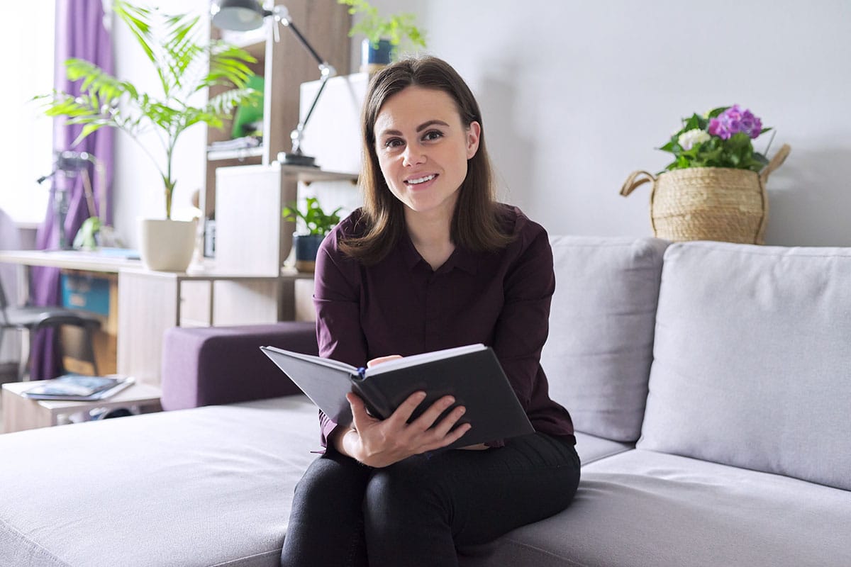 a person with one of many mental health jobs in maryland sits on a couch holding a notebook