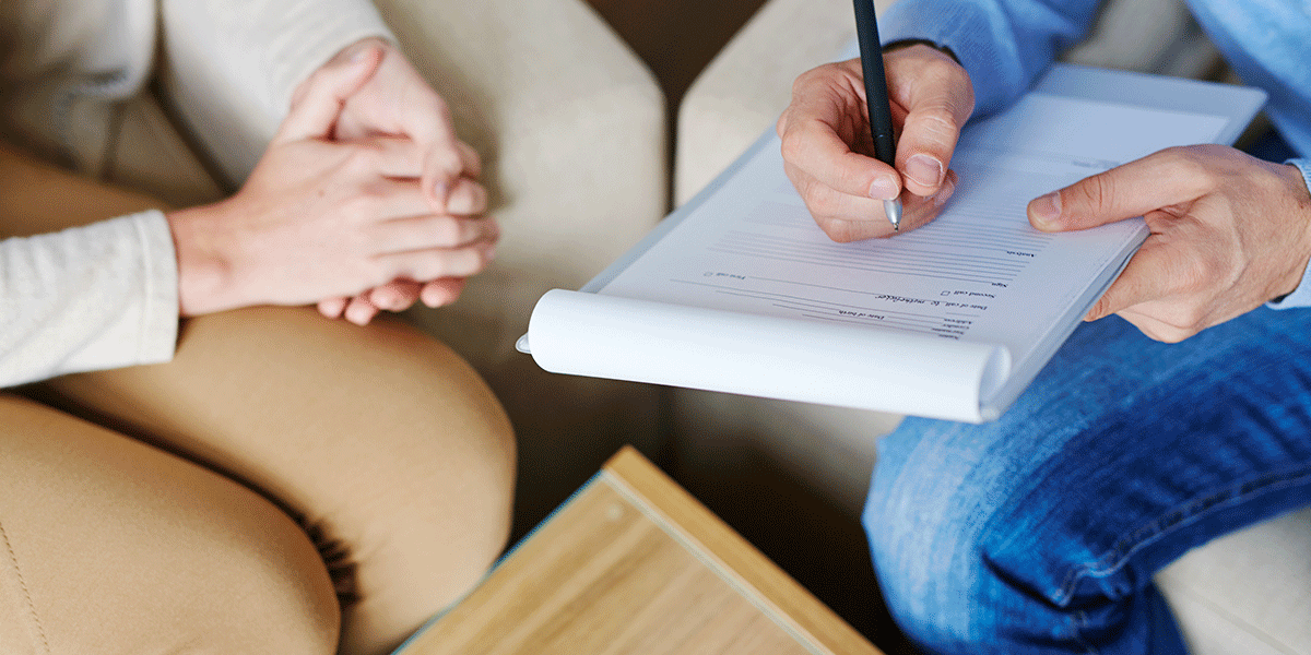 a behavioral health technician helps a patient fill out their intake paperwork at a facility