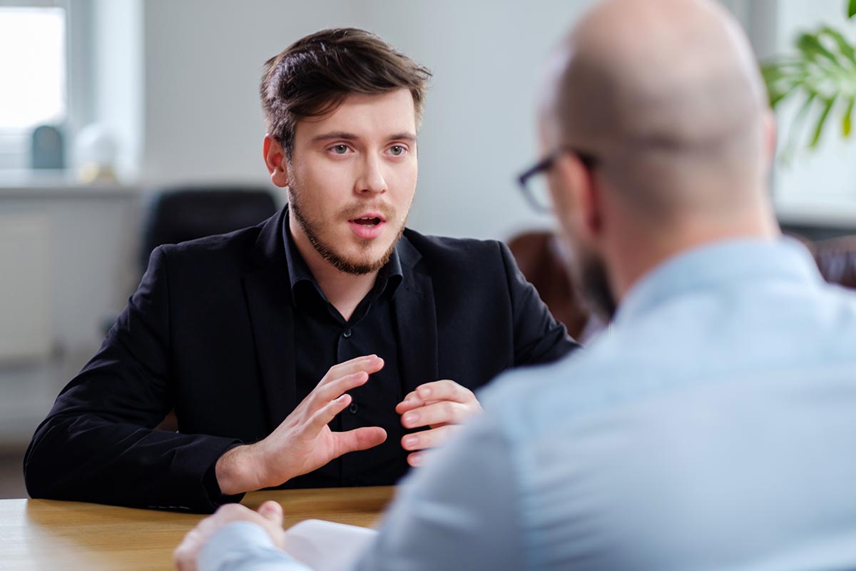 a young man confidently and professionally asks his boss for a promotion at work