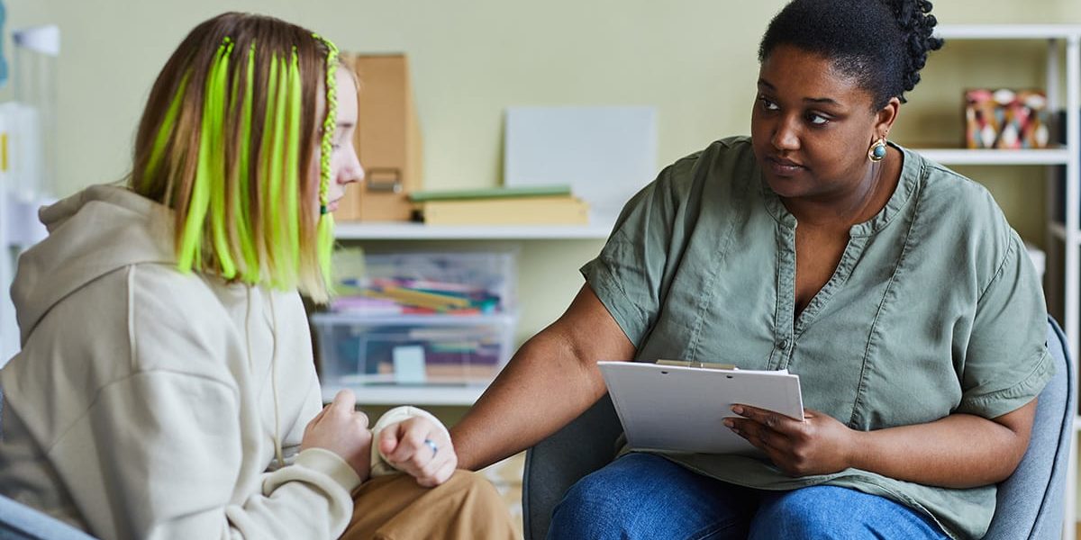 a social worker meets with a teen undergoing addiction and mental health treatment to assess their needs and progress